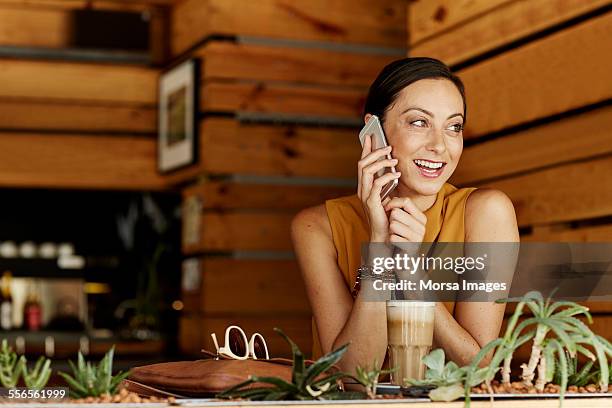 happy woman answering smart phone at cafe table - iced coffee stock pictures, royalty-free photos & images