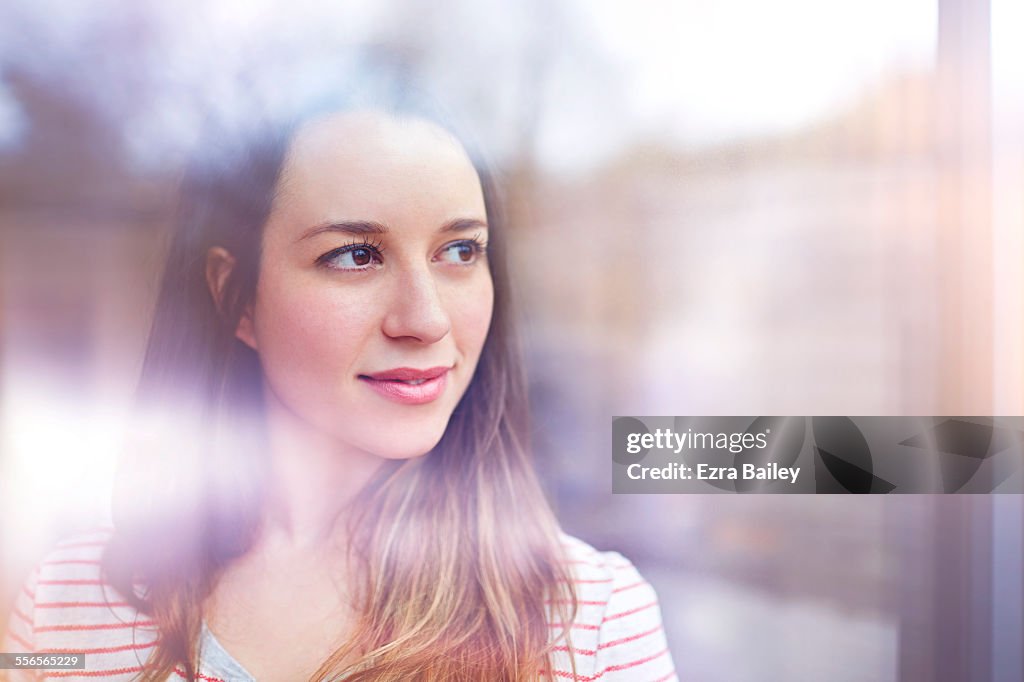 Young woman gazes thoughtfully through window
