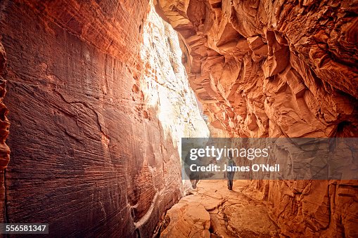 female hiker walking through red cave