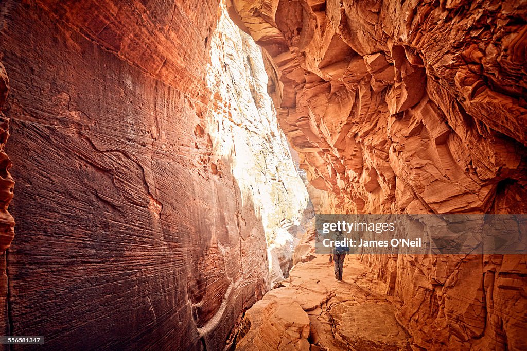 Female hiker walking through red cave