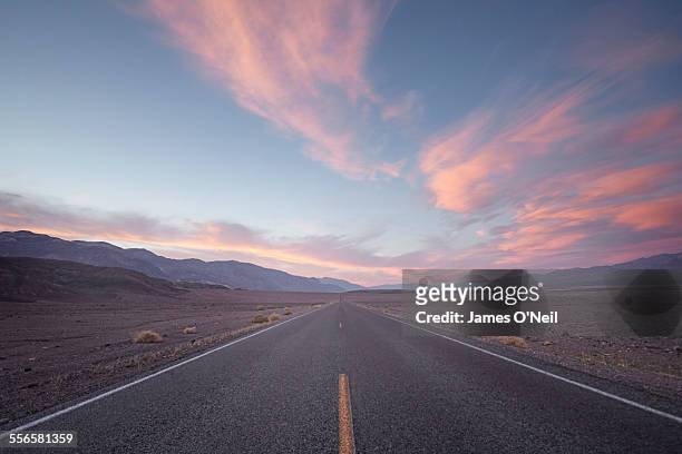 straight road in desert at sunset - straßenverkehr stock-fotos und bilder