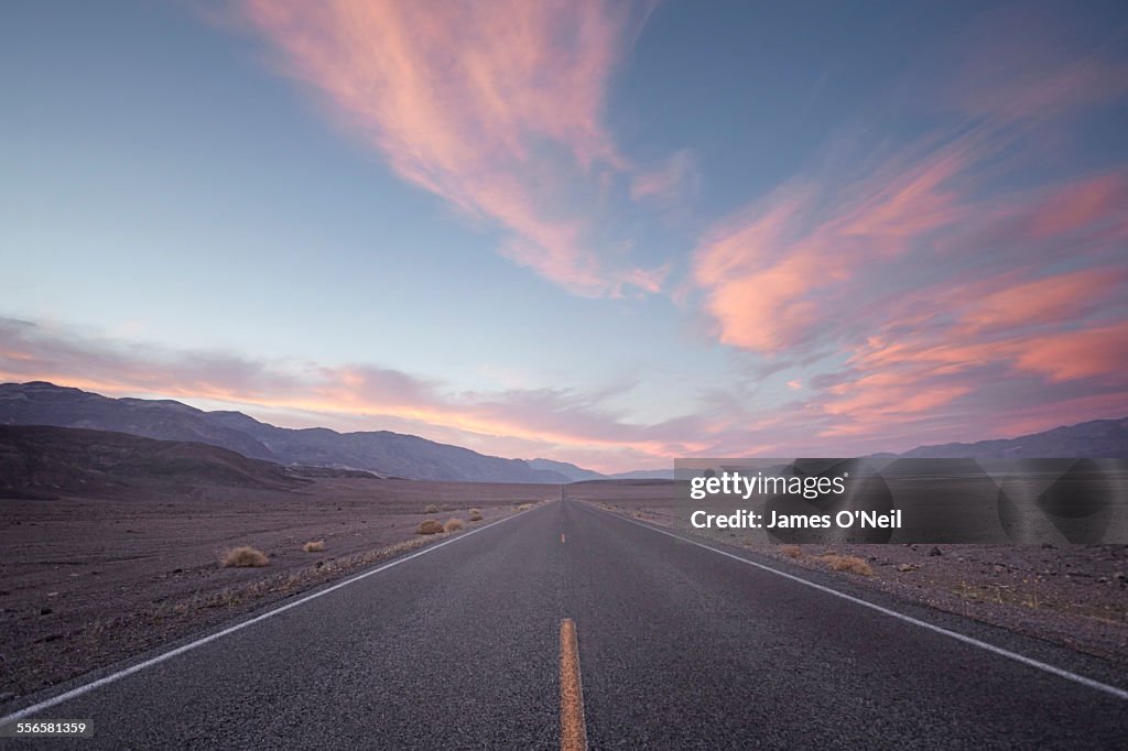 Straight road in desert at sunset