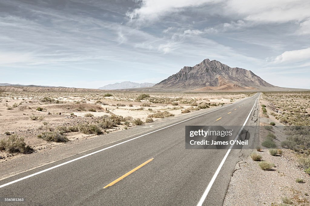 Straight road in desert with distant mountain.