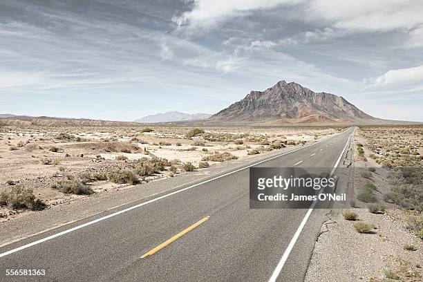 straight road in desert with distant mountain. - death valley stock pictures, royalty-free photos & images