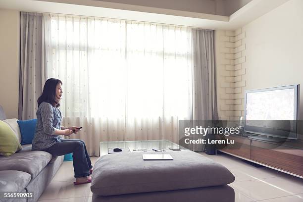 woman watching tv in living room - leren schoen stock-fotos und bilder