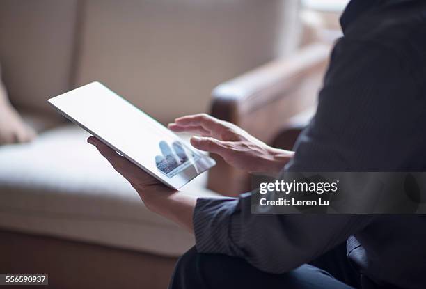 man using digital tablet on sofa - ipad hand foto e immagini stock