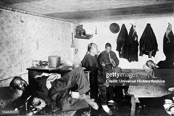 Interior of Chinese lodging house ; San Francisco, California. Four Chinese men smoking opium pipes in Chinatown, c 1900.