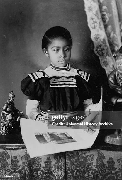 African American girl, half-length portrait, standing at table with illustrated book, facing slightly right. Types of American Negroes, compiled and...