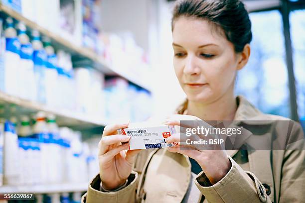 Interior of Chemists Shop, Woman holding ibuprofen drug.