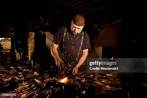 blacksmith working with hammer at anvil surrounded by sparks - blacksmith sparks stock pictures, royalty-free photos & images