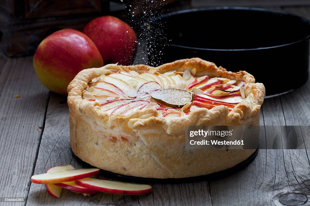 Sprinkling baked apple pie with icing sugar