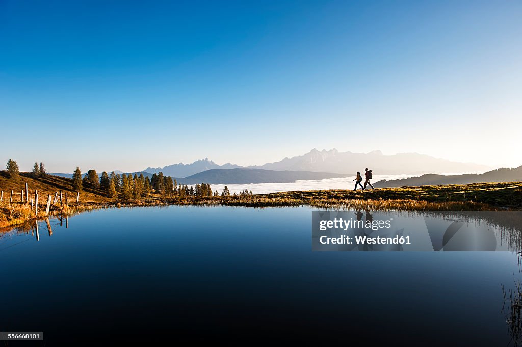 Austria, Altenmarkt-Zauchensee, hikers at mountain lake in the Lower Tauern