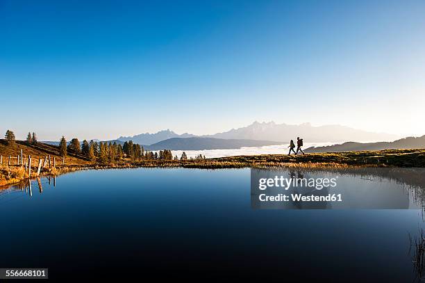 austria, altenmarkt-zauchensee, hikers at mountain lake in the lower tauern - distant stock pictures, royalty-free photos & images