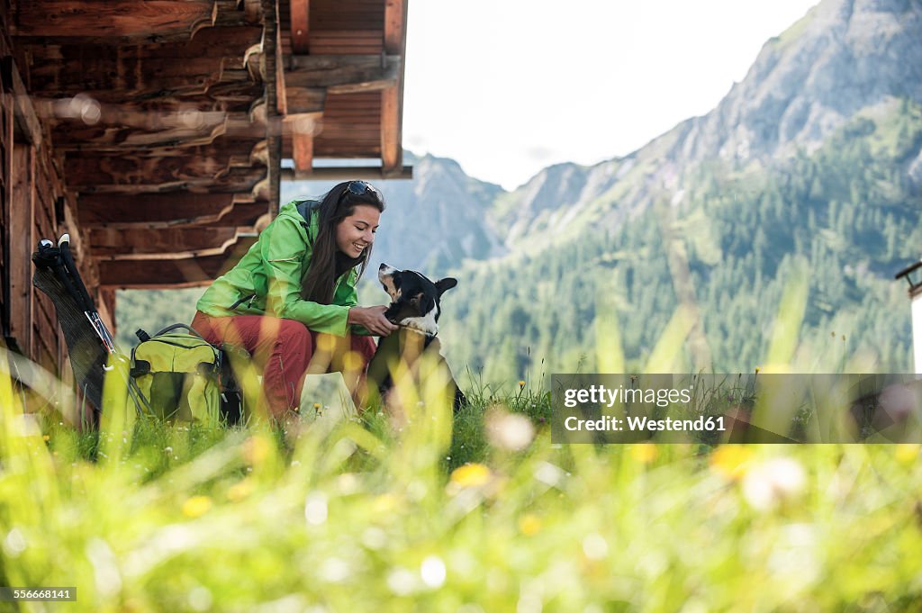 Austria, Altenmarkt-Zauchensee, young woman with dog at alpine cabin