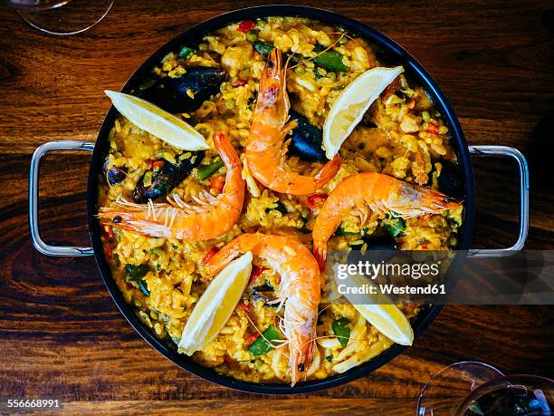 fresh paella in pan on wooden table - paella stock-fotos und bilder