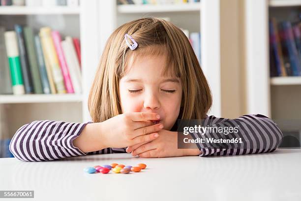 little girl eating chocolate buttons - eating candy stock-fotos und bilder