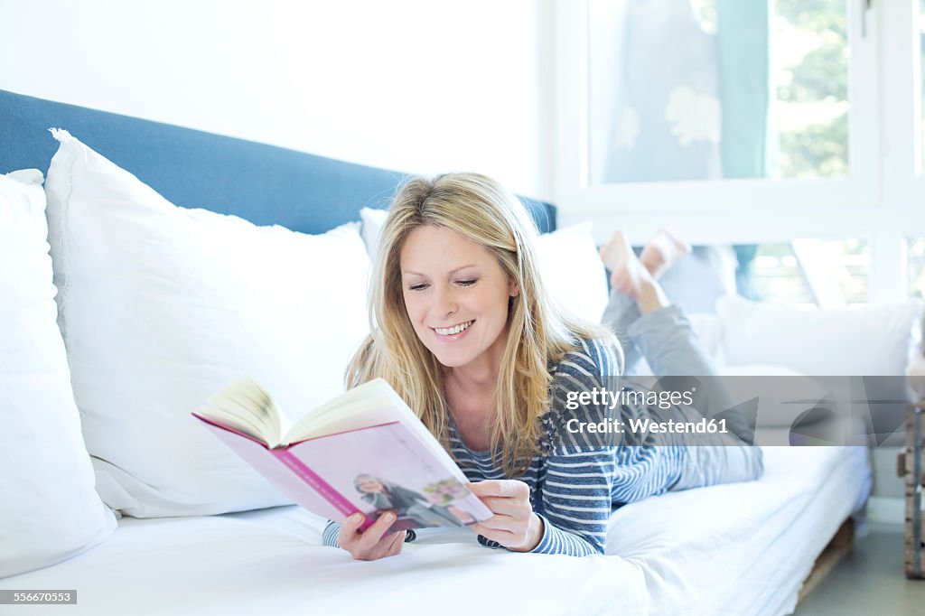 Woman lying on couch reading a book