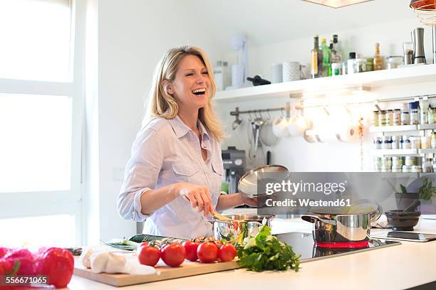 happy woman cooking in kitchen - woman cooking stock pictures, royalty-free photos & images