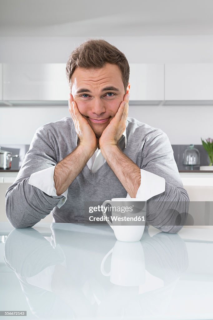 Portrait of man with head in his hands sitting at kitchen table