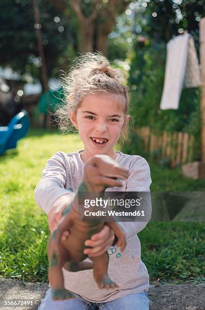 girl holding a toy dinosaur outdoors - dinosaur toy i - fotografias e filmes do acervo