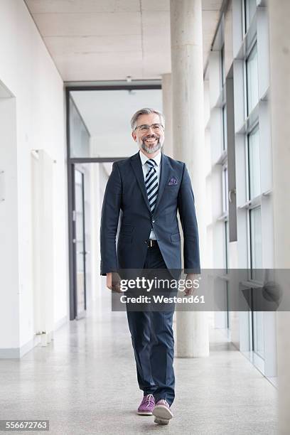 confident businessman walking on hallway - front on portrait older full body foto e immagini stock