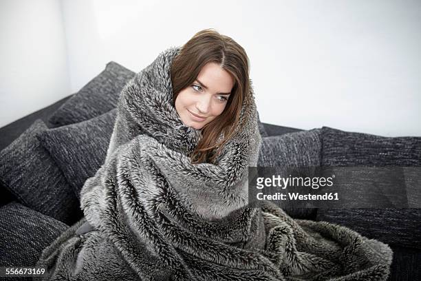 young woman on couch wrapped in fur blanket - wrapped in a blanket stock pictures, royalty-free photos & images