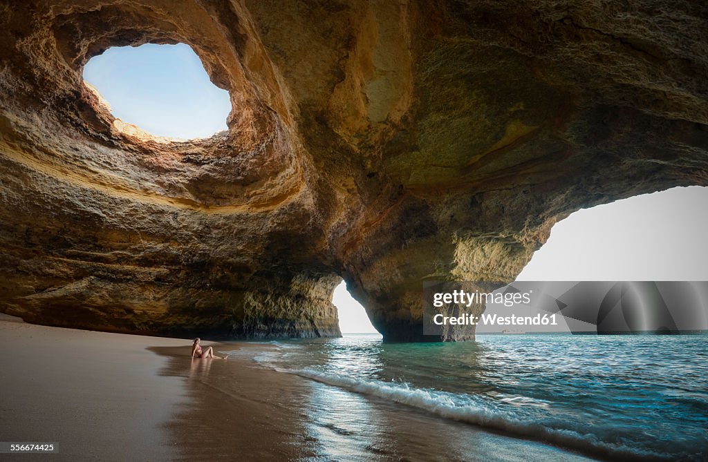 Portugal, beach of Benagil, cave, woman sitting at seafront
