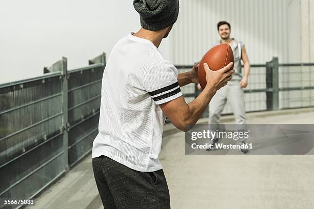 two young men playing with football on road - throwing football stock pictures, royalty-free photos & images