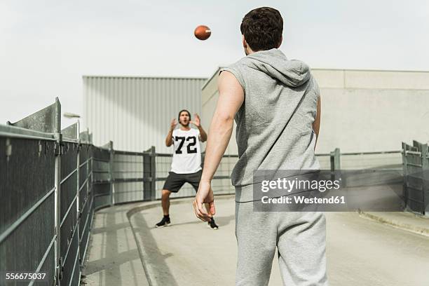 two young men playing with football on road - catching stock pictures, royalty-free photos & images