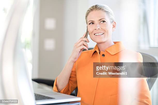 portrait of businesswoman telephoning in an office - orange blazer stock pictures, royalty-free photos & images