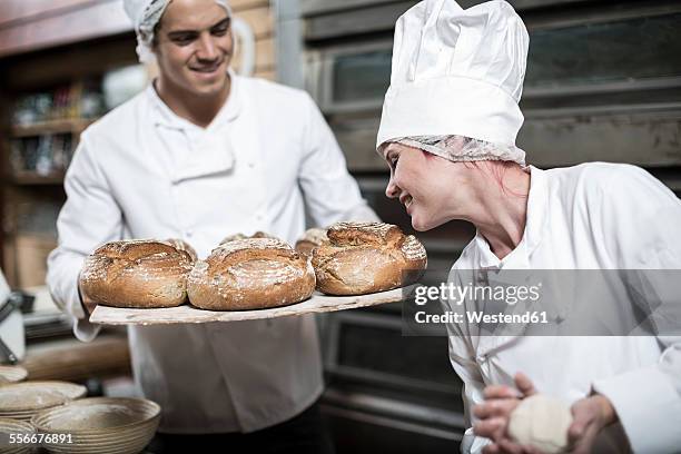 female baker smelling fresh bread - baker smelling bread stockfoto's en -beelden