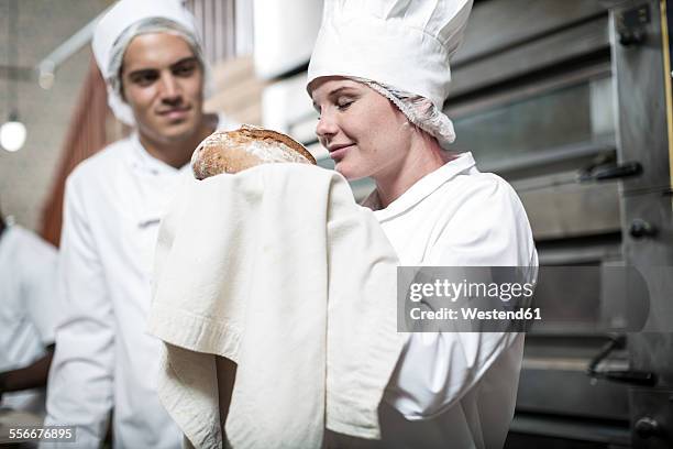 female baker excited over baked bread fresh from the oven - baker smelling bread stock-fotos und bilder