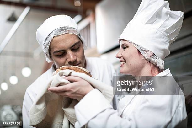 female baker excited over baked bread fresh from the oven - baker smelling bread photos et images de collection