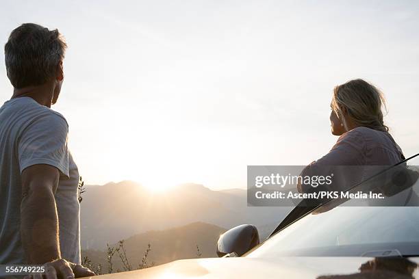 couple stand by car door, look to sunrise, hills - two cars ストックフォトと画像