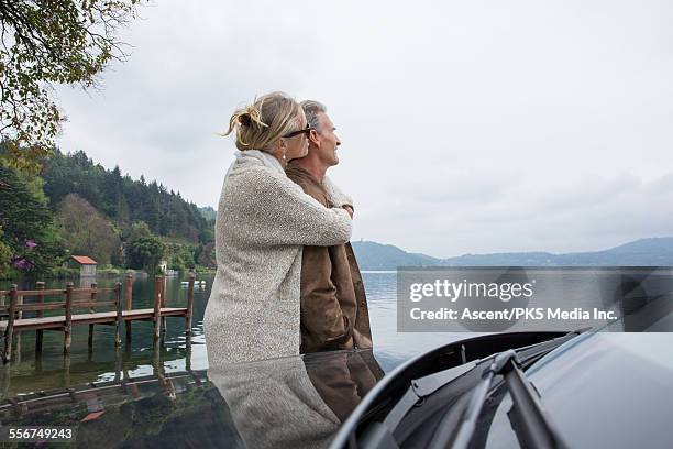 couple embrace at edge of lake, beside car - car top view foto e immagini stock