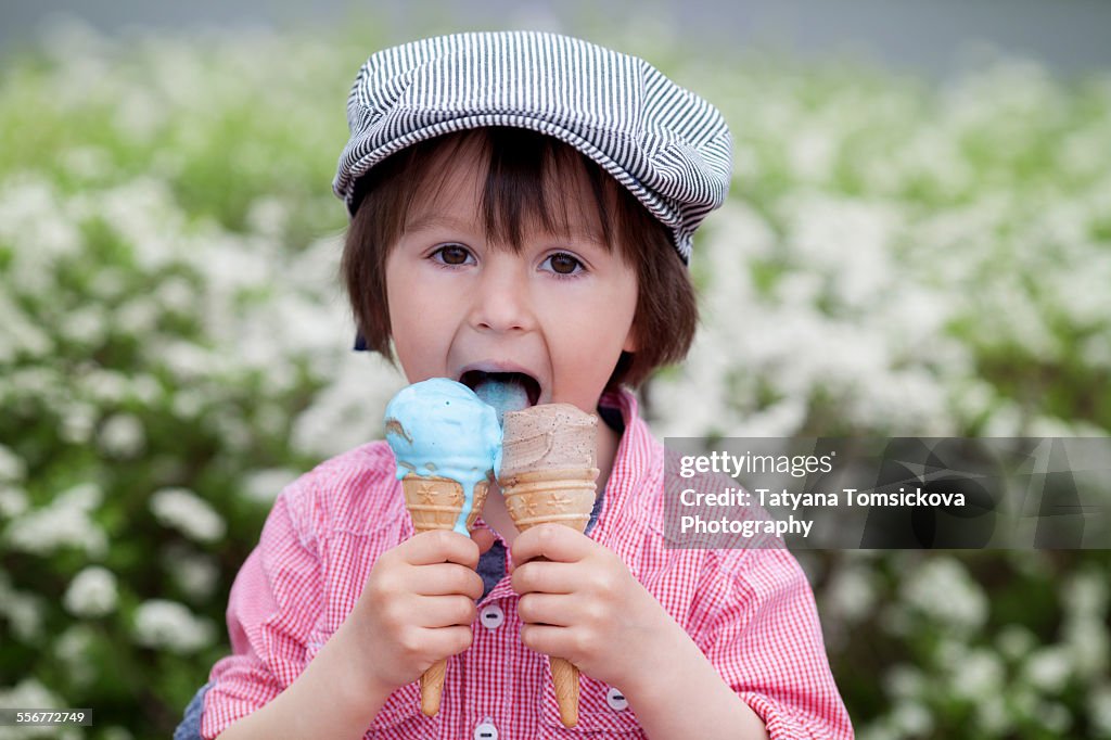 Cute boy, eating two ice creams in the park