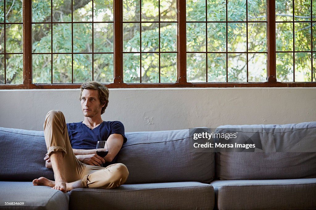 Man holding red wineglass on sofa