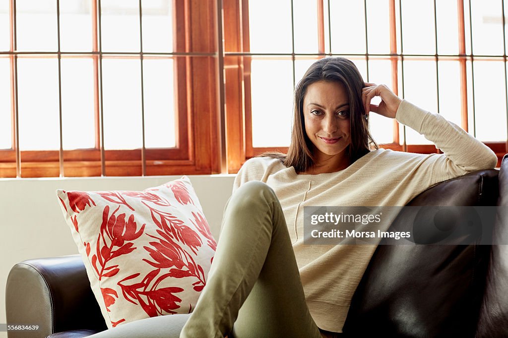 Smiling woman sitting on sofa at home