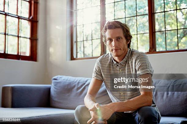 man sitting on sofa at home - at home portrait fotografías e imágenes de stock