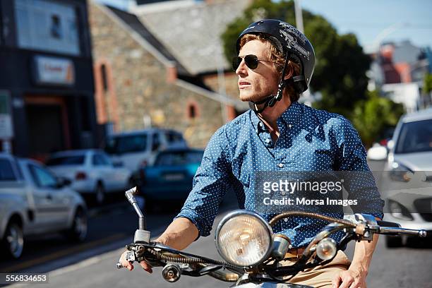 man riding motorcycle on city street - crash helmet fotografías e imágenes de stock