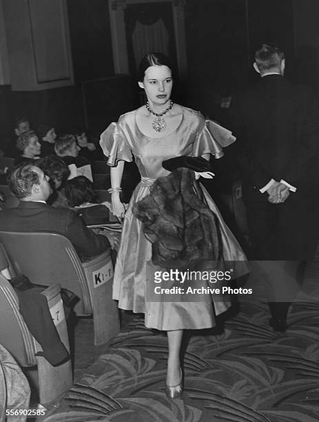 American artist, author, and actress Gloria Vanderbilt walking up the aisle of a theatre, 25th March 1952.