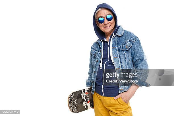 fashionable old man holding a skateboard - jong van hart stockfoto's en -beelden