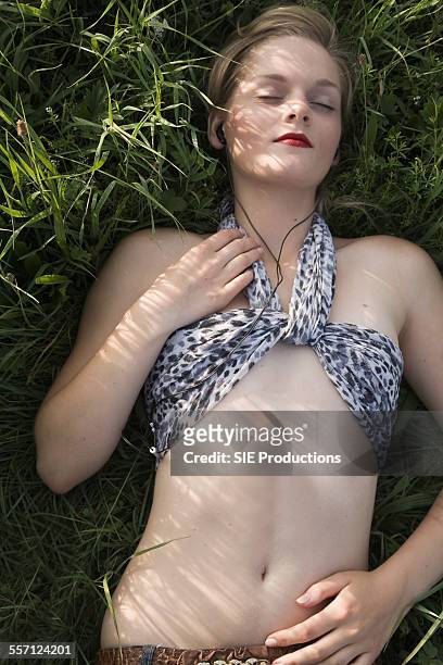 young woman lying on grass and listening to music - sie productions foto e immagini stock
