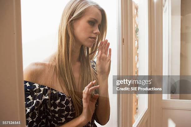 young woman looking though window - sie productions foto e immagini stock