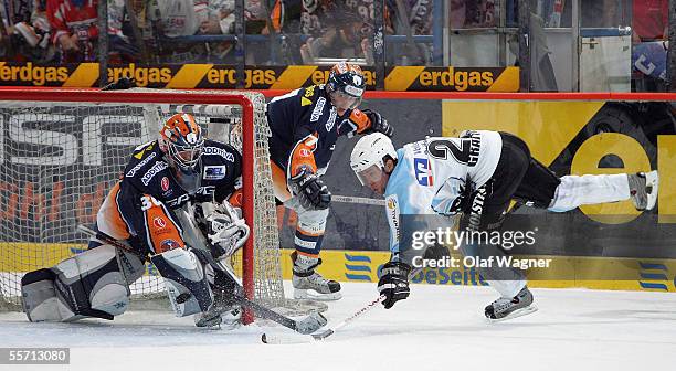 Daniar Dshunussow and Frank Hoerdeler from Eisbaeren Berlin and Benoit Gratton from Hamburg Freezers compete during the DEL match between Eisbaeren...