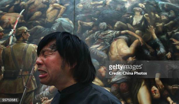 Chinese artist Li Zijian condemns the atrocity of Japanese troops in front of his canvas work "Nanjing Massacre", shown at the Memorial For Nanjing...
