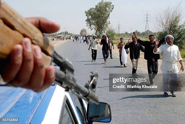 An Iraqi soldier stands guard as Shiite pilgrims walk towards the holy Shiite city of Karbala September 18, 2005 which is located approximately 70...