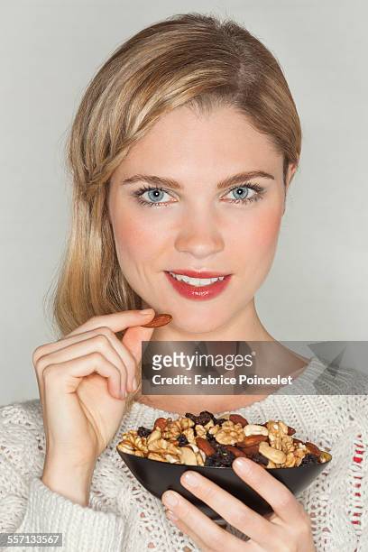 portrait of a beautiful woman eating dried fruit - blond women happy eating stock pictures, royalty-free photos & images