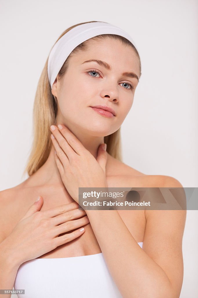 Beautiful woman applying moisturizer on her neck