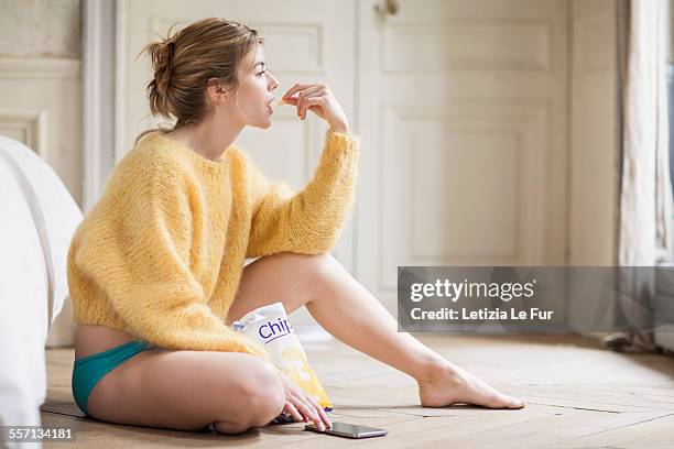 woman using phone and eating chips - woman junk food eating stockfoto's en -beelden